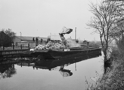 850490 Afbeelding van het storten van huisvuil in vuilnisschuiten in de Biltsche Grift op het Vaaltterrein te Utrecht.